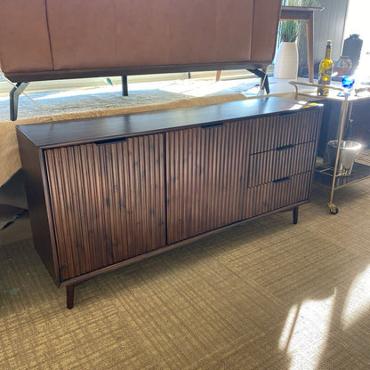 Wooden sideboard in a room with a rug and furniture.