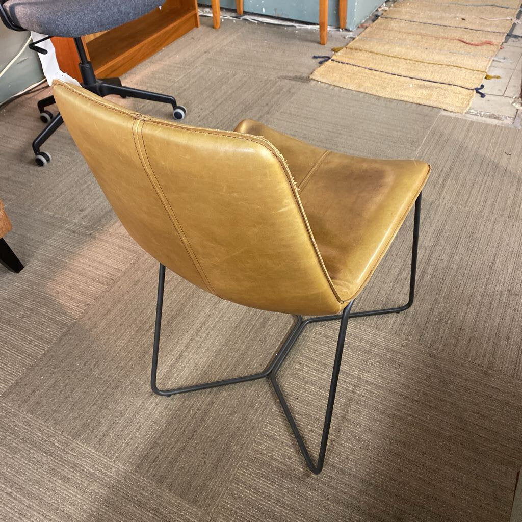 Brown leather chair with black metal legs on a carpeted floor.
