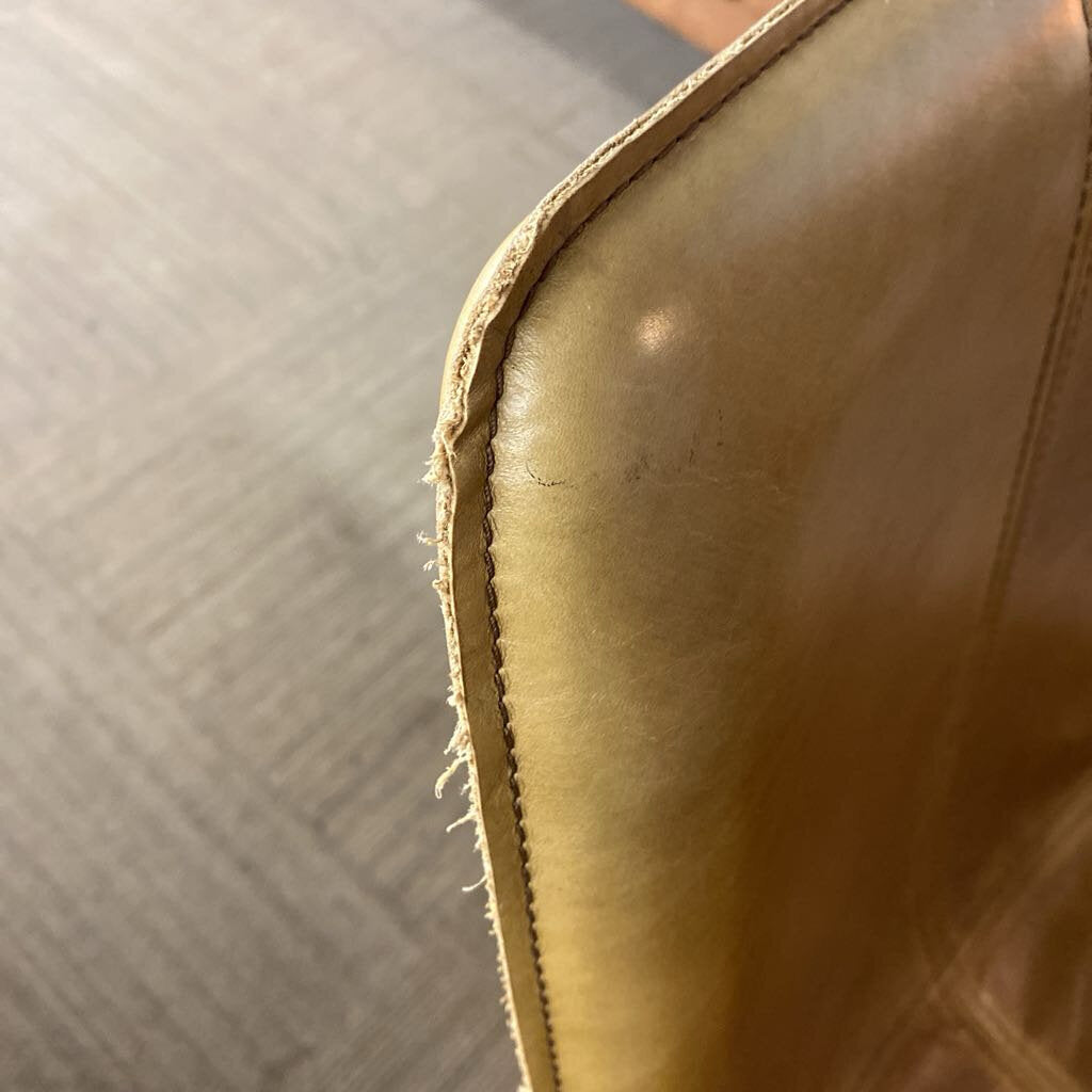 Close-up of a leather product with visible stitching on a neutral background