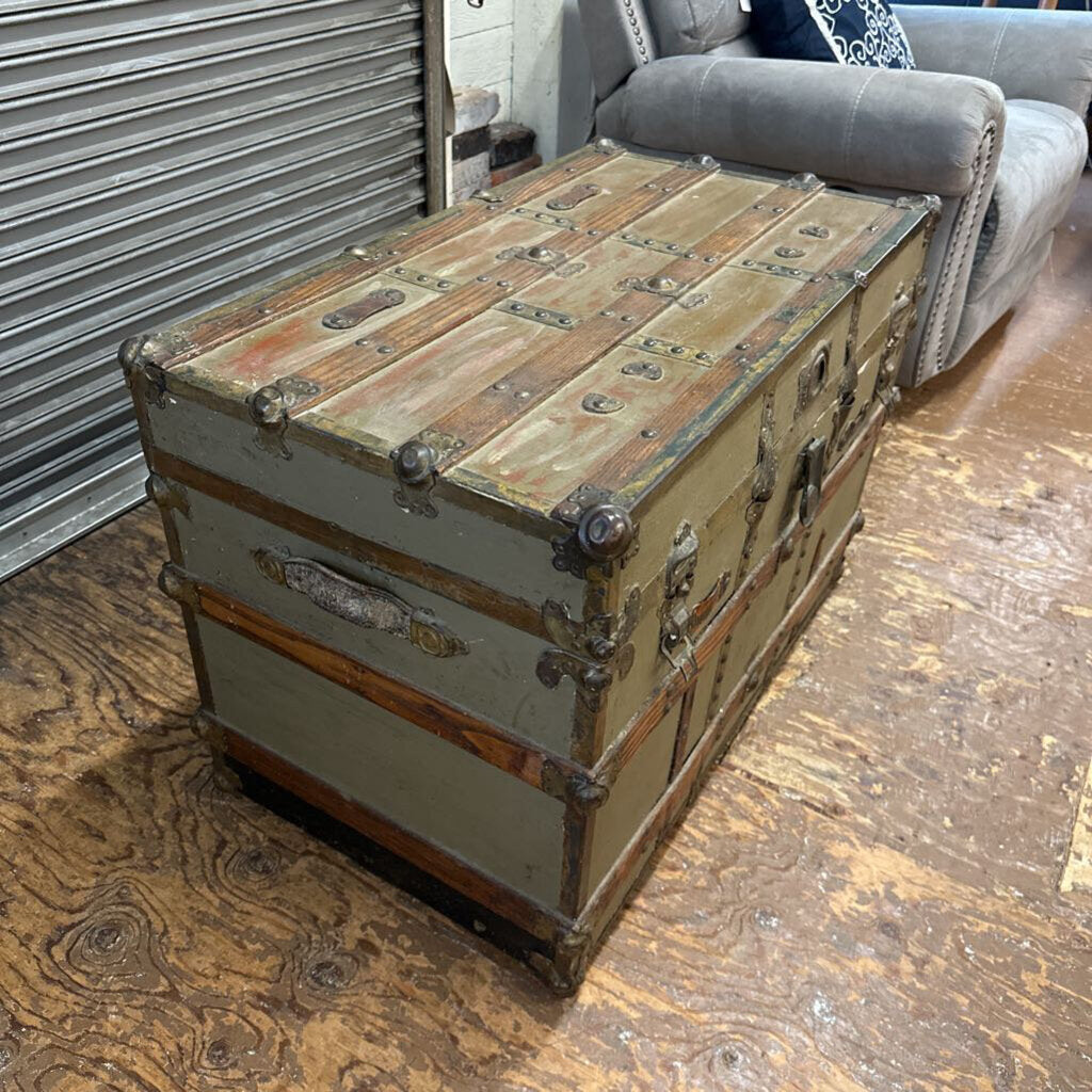 Vintage-style wooden trunk used as a coffee table on a wooden floor.