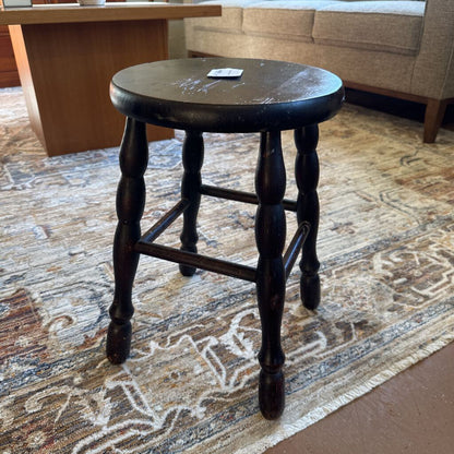Wooden stool on a patterned rug with a blurred background