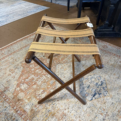 Wooden folding stool with woven seat on a patterned rug