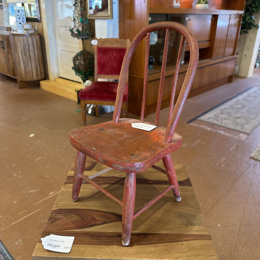 Vintage wooden chair with a red-painted seat on display in an indoor setting.