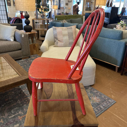 Red chair in a furniture store with various couches and decor items in the background.