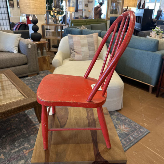 Red chair in a furniture store with various couches and decor items in the background.