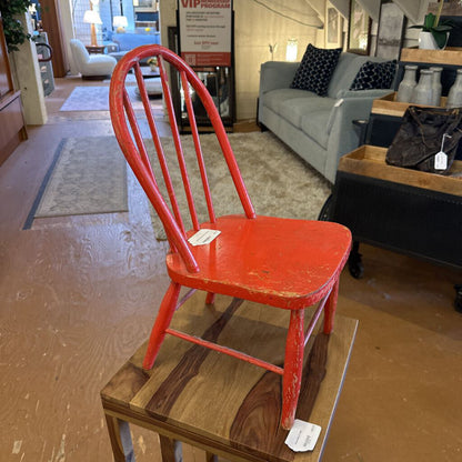 Red chair on a wooden platform in a store setting with furniture in the background