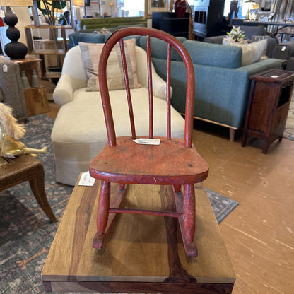 Red wooden rocking chair on a wooden table in a furniture store setting
