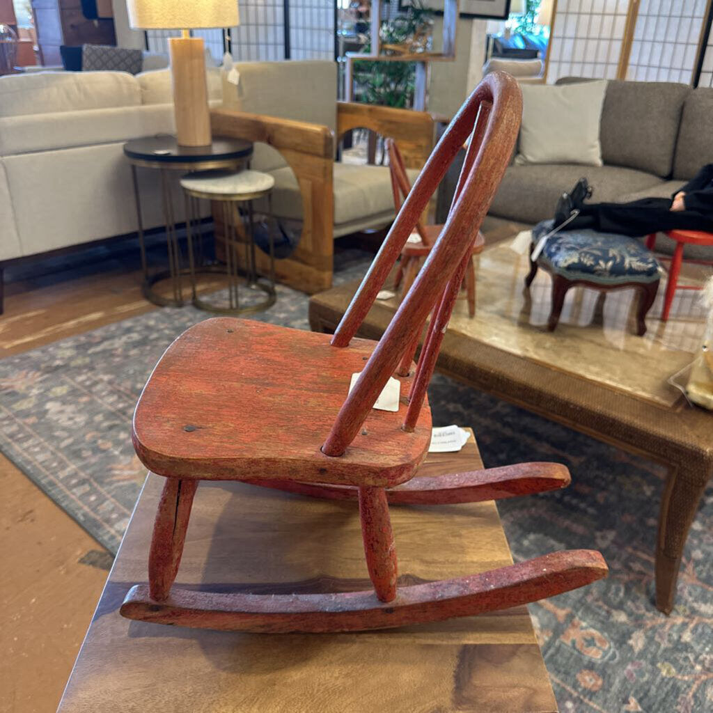 Small wooden rocking chair on a table with a living room setting in the background