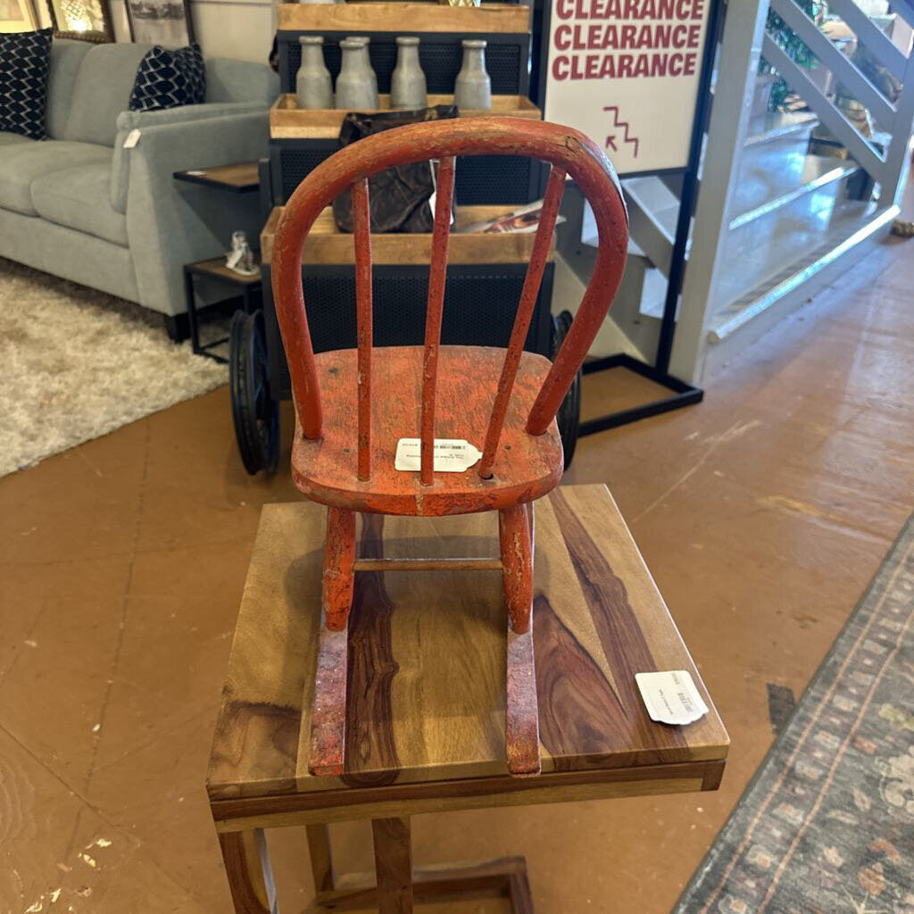 Wooden chair on a wooden platform in a store setting with furniture and clearance signs in the background.