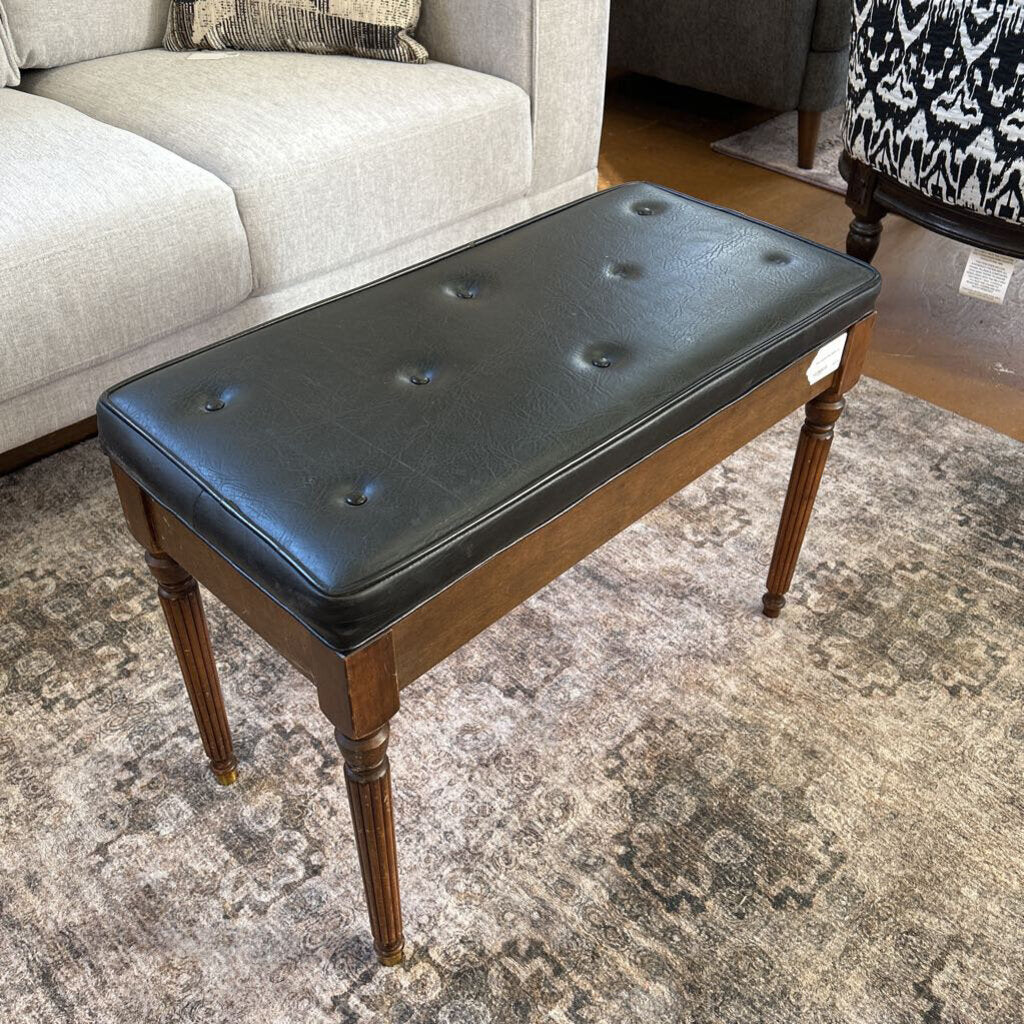 Black leather bench with wooden legs in a living room setting