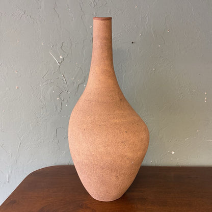Terracotta vase on a wooden surface with a gray wall background