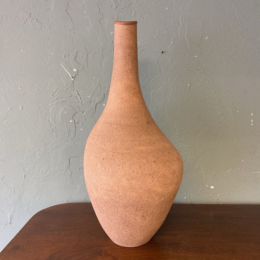 Terracotta vase on a wooden surface with a gray wall background