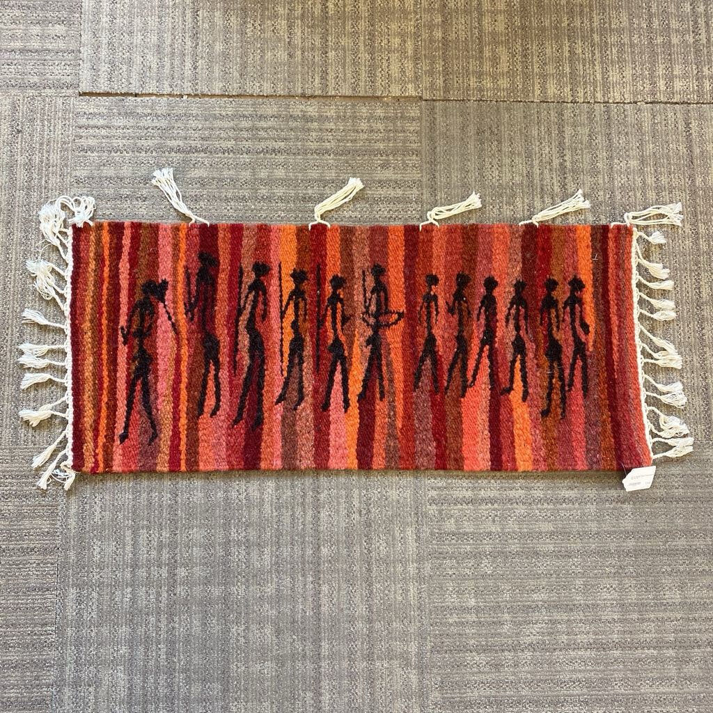 Small rug with striped pattern and black figures on a textured surface