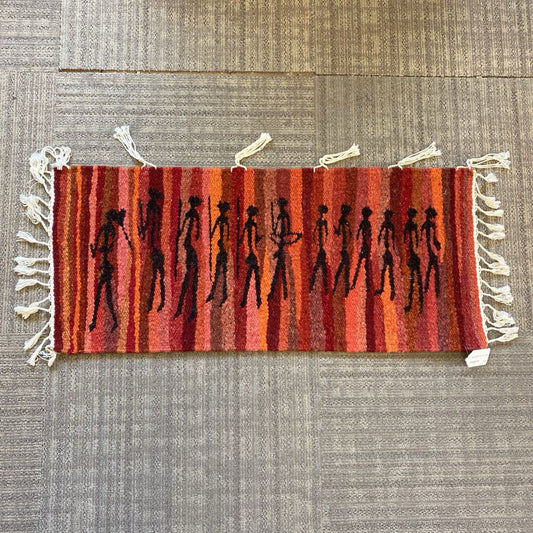 Small rug with striped pattern and black figures on a textured surface