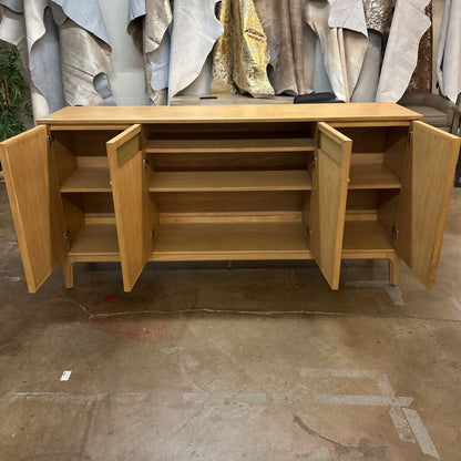 Wooden sideboard with open doors on a concrete floor