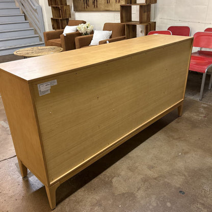 Wooden cabinet in a storage or warehouse setting with furniture in the background.