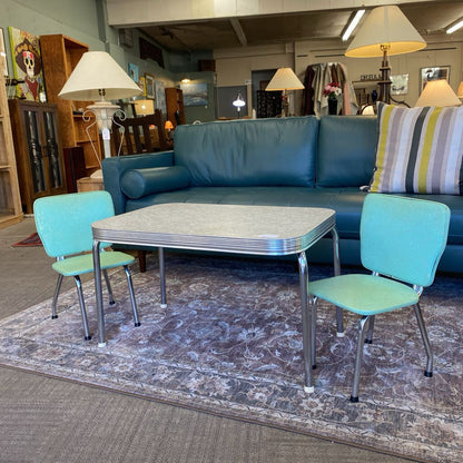 Blue sectional sofa with matching chairs and a table in a furniture store setting.
