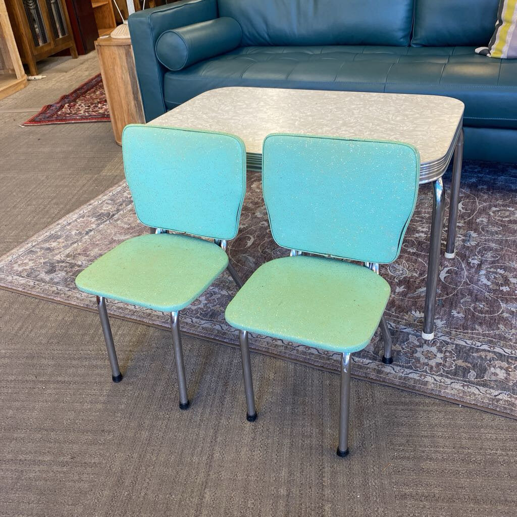 Two turquoise chairs with green seats on a patterned rug in a living room setting.