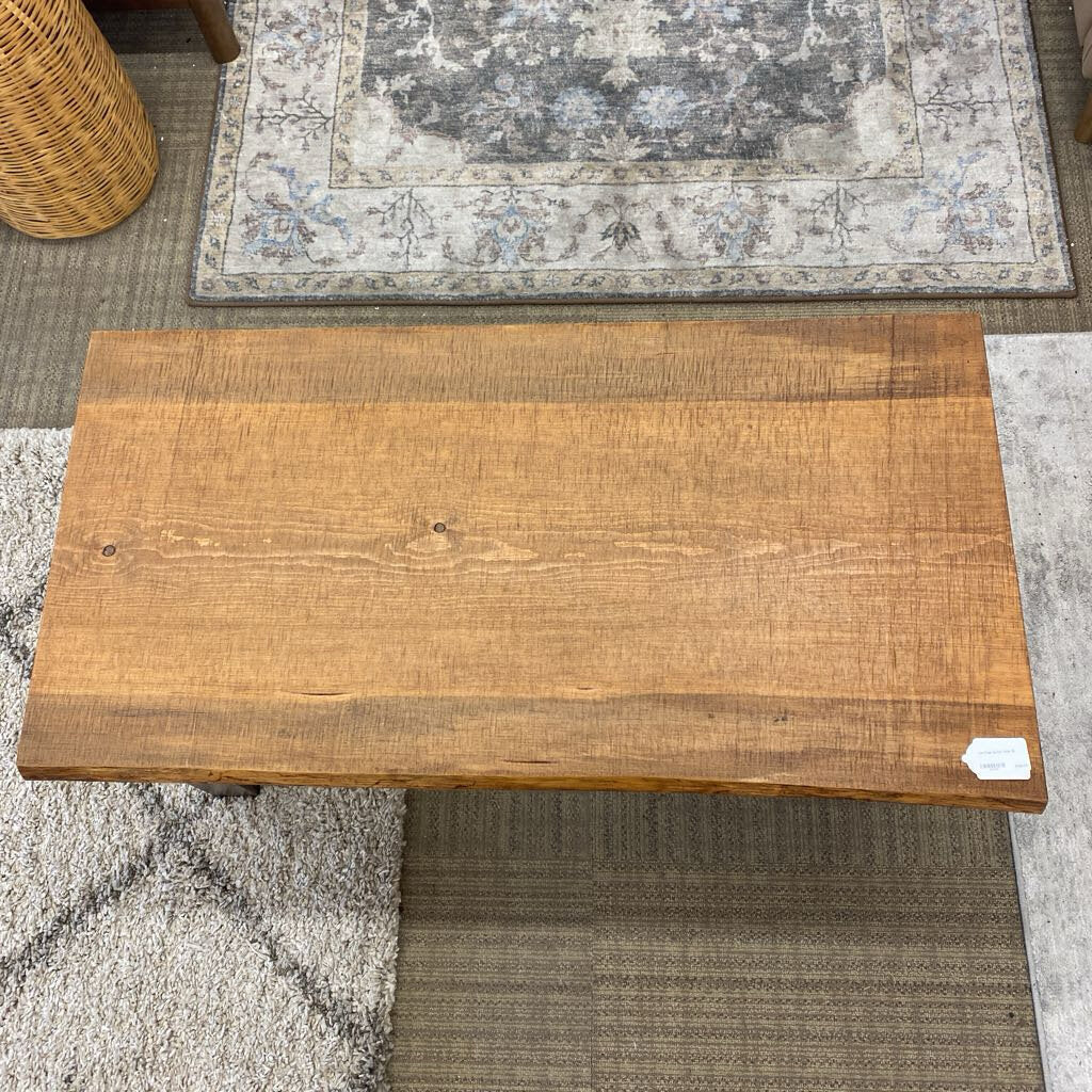 Wooden bench on a textured floor with a rug in the background