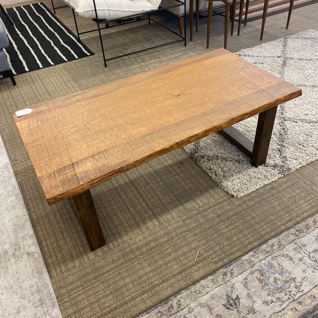 Wooden coffee table on a patterned rug with a striped rug in the background