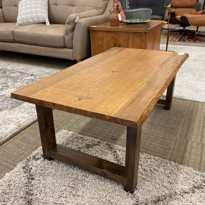 Wooden coffee table in a living room setting with a sofa and rug.