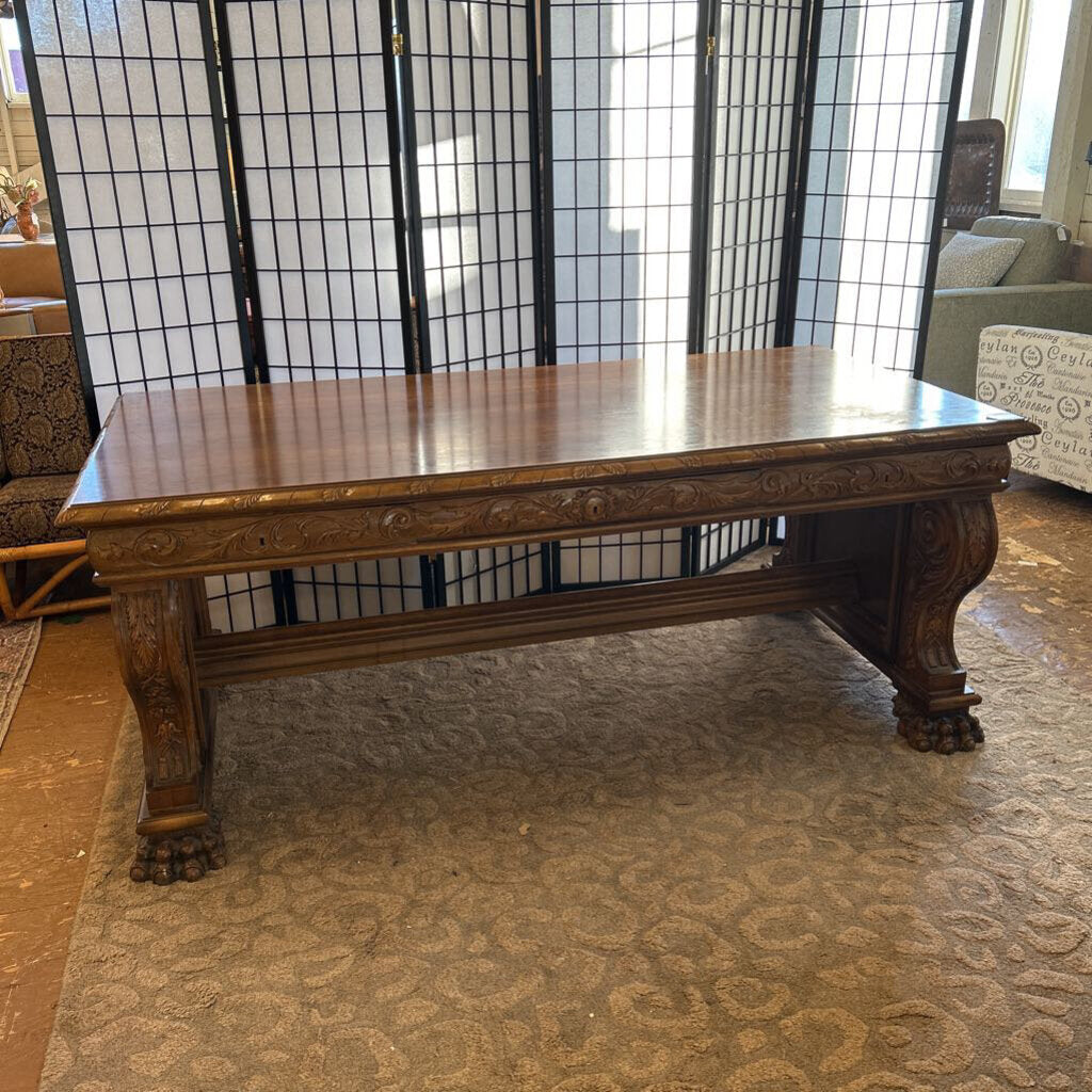 Wooden table with decorative carvings in a room with a black lattice screen.