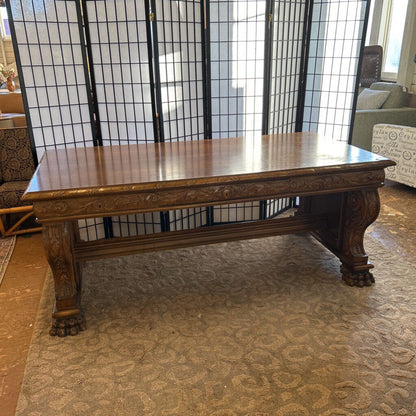 Wooden table with decorative carvings in a room with a black lattice screen.