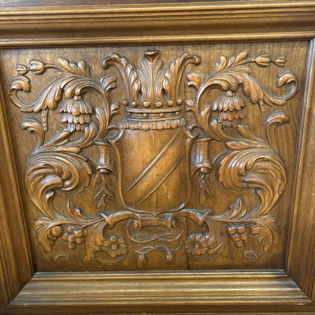 Wooden panel with intricate carvings of a shield and floral elements