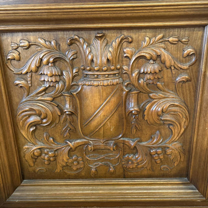 Wooden panel with intricate carvings of a shield and floral elements