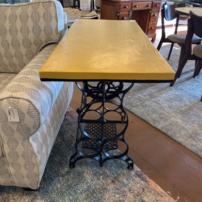 Yellow table with a black metal base in a room with furniture and decor.