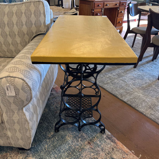 Yellow table with a black metal base in a room with furniture and decor.