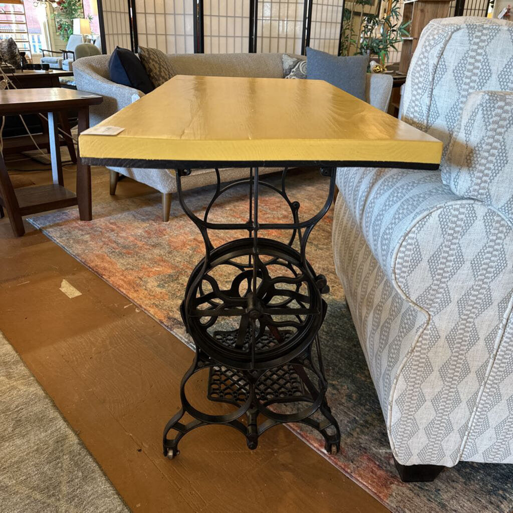 Yellow table with a black metal base in a room with furniture and decor.