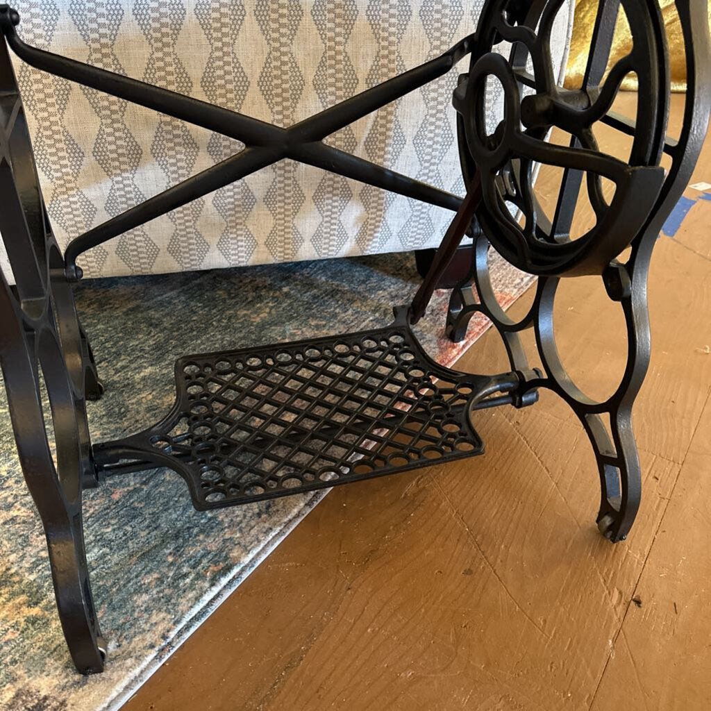 Decorative metal bench with intricate design on a wooden floor.
