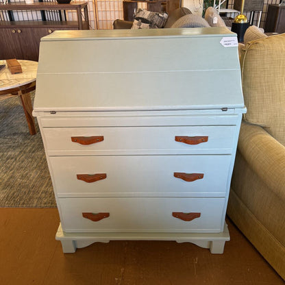 Light blue wooden desk with brown handles in a room setting