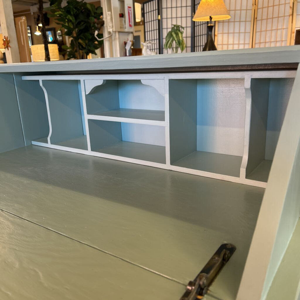 Unfinished wooden shelf with a light blue finish in a room setting.