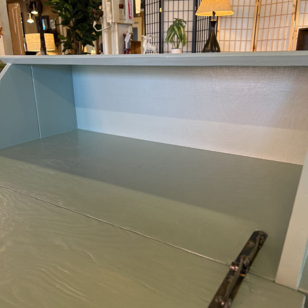Counter with a light blue wall and white ceiling in a room with plants and lamps.