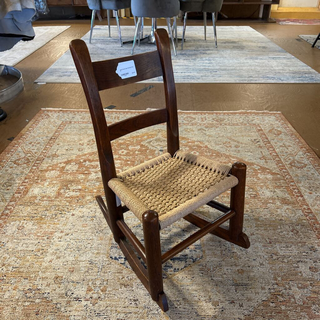 Wooden rocking chair with woven seat on a patterned rug