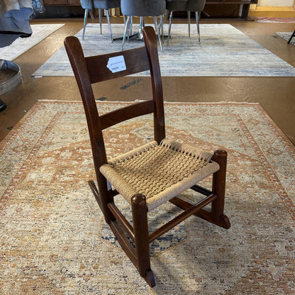 Wooden rocking chair with woven seat on a patterned rug