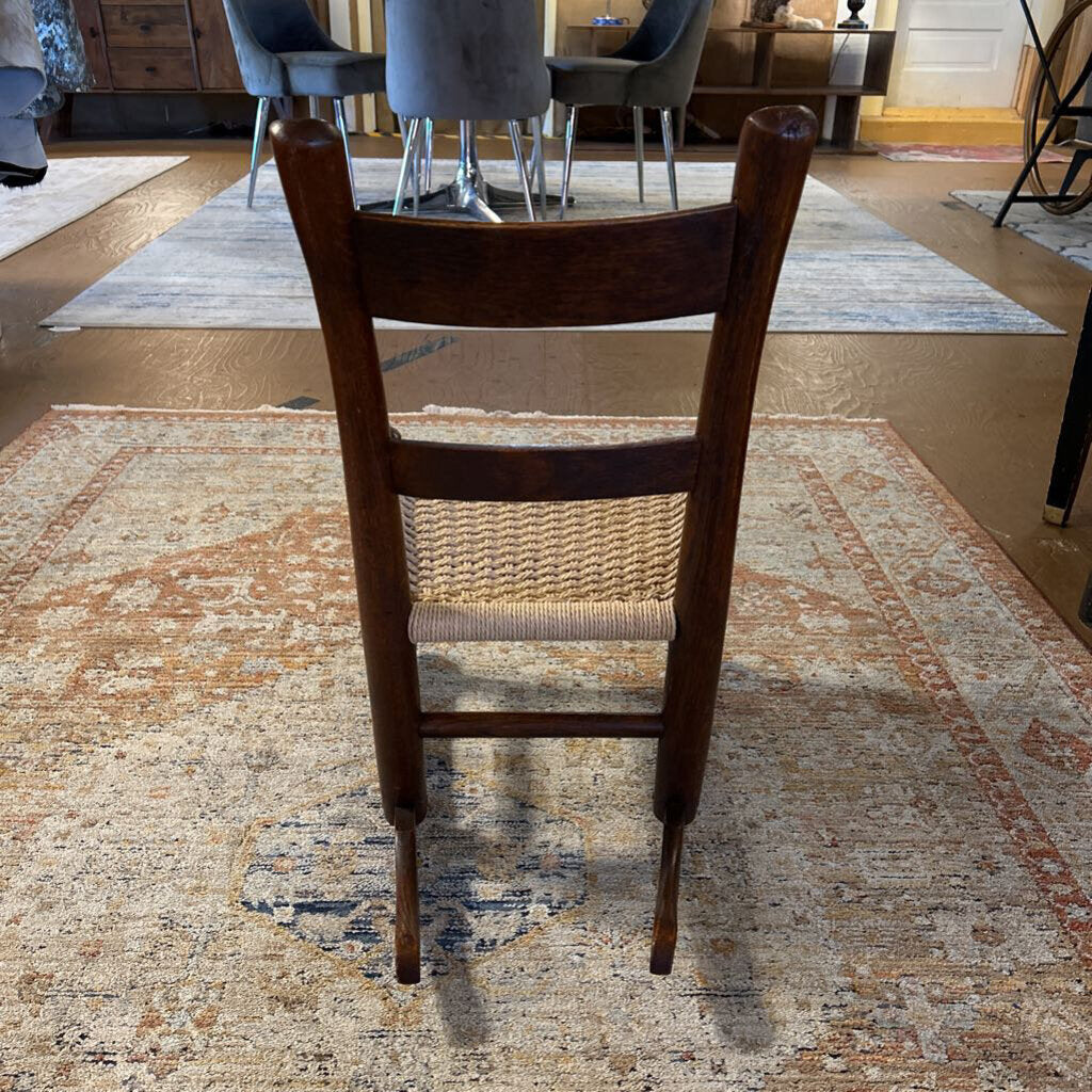 Wooden chair on a patterned rug with a dining area in the background