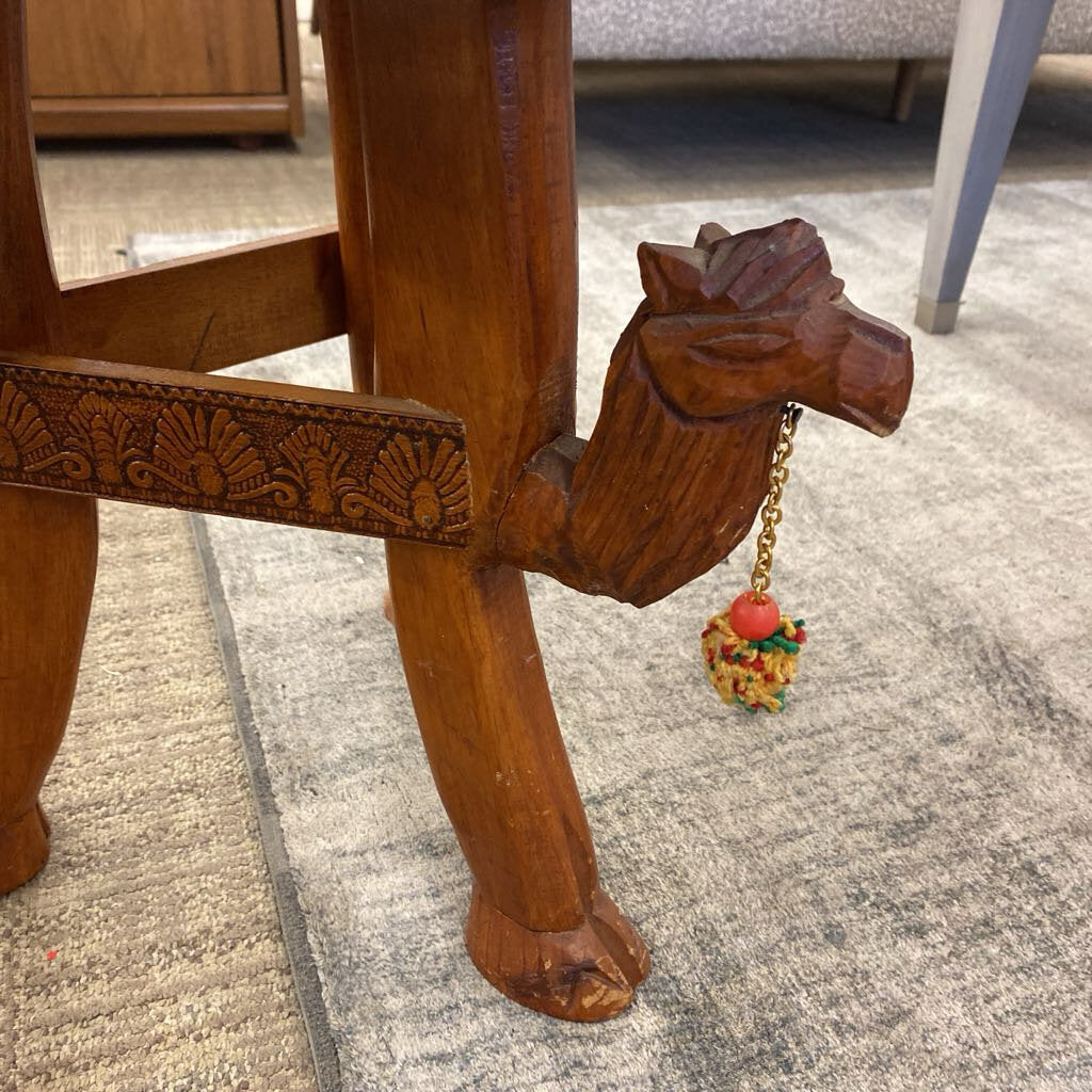 Wooden chair leg with intricate carvings and a decorative heart charm on a carpeted floor.