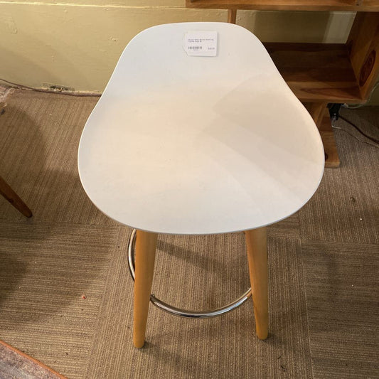 White stool with wooden legs on a carpeted floor