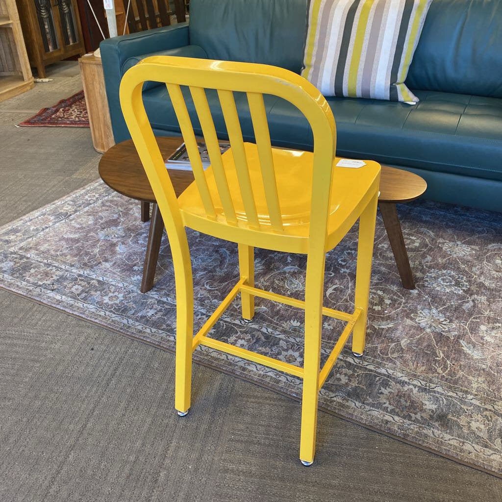 Yellow chair in a room with a blue couch and patterned rug.