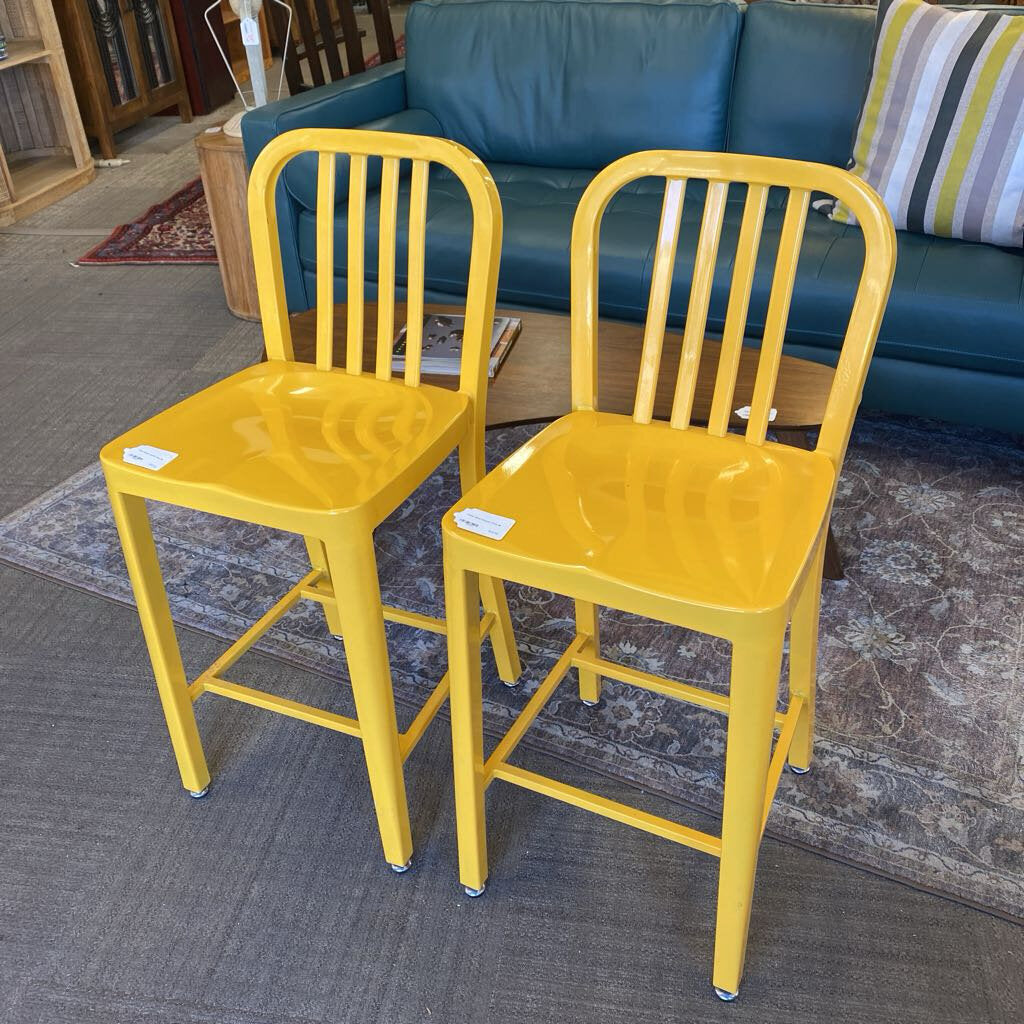 Two yellow bar stools in front of a blue couch.