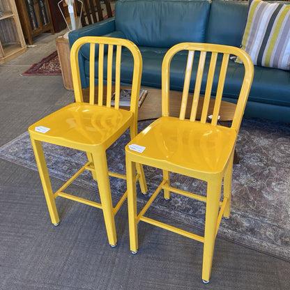 Two yellow bar stools in front of a blue couch.