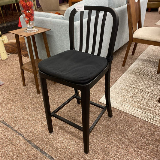 Black bar stool with a cushioned seat in an indoor setting