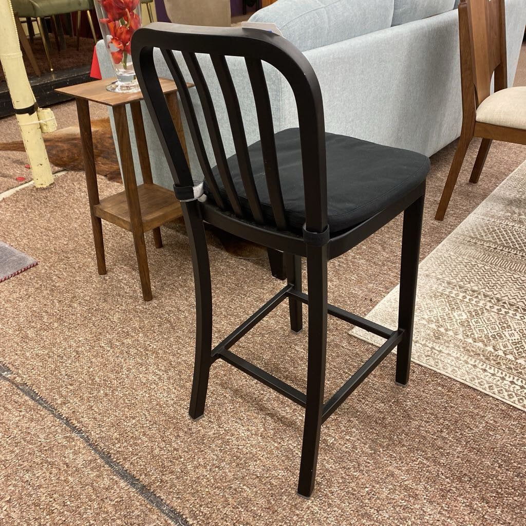 Black bar stool with slatted backrest on a carpeted floor