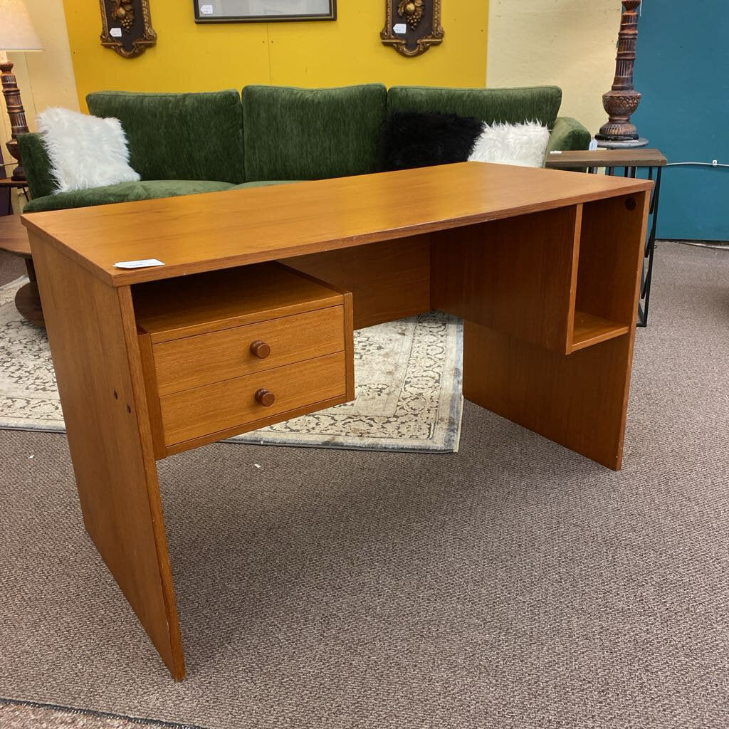 Wooden desk with a drawer in a room with a green couch and yellow wall.