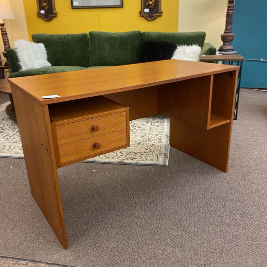 Wooden desk with a drawer in a room with a green couch and yellow wall.