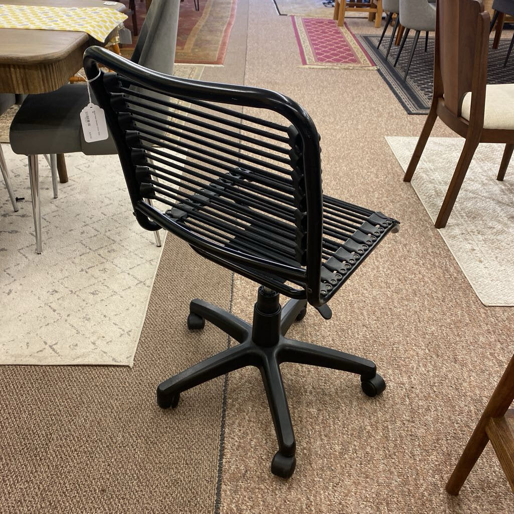 Black office chair on a carpeted floor with other furniture in the background