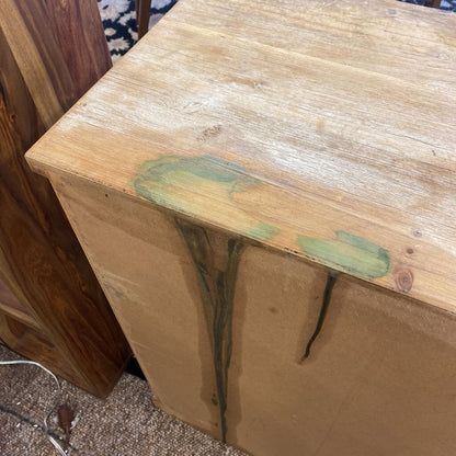 Wooden table with green paint splashes on a carpeted floor